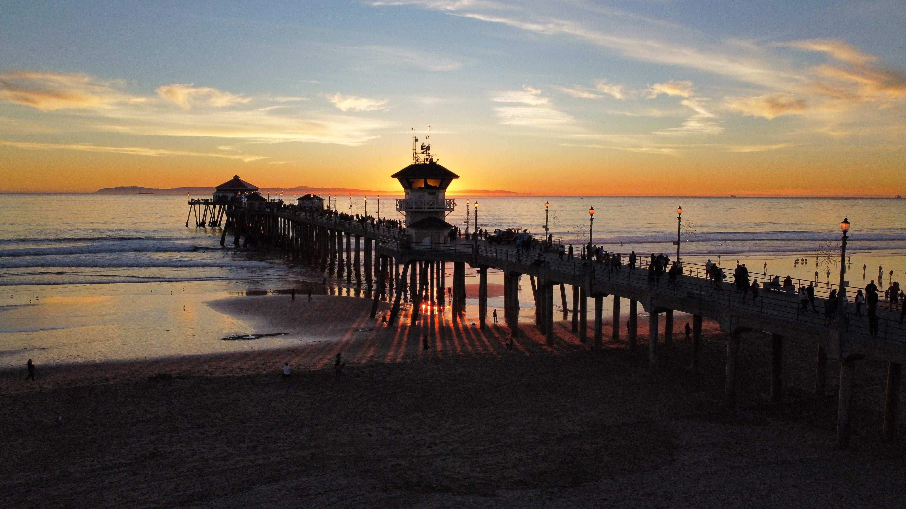Pier at sunset with people enjoying the view on a beach