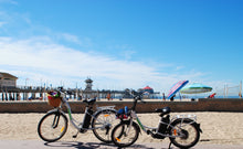 Load image into Gallery viewer, Adult and child electric bicycles at the Huntington Beach pier.
