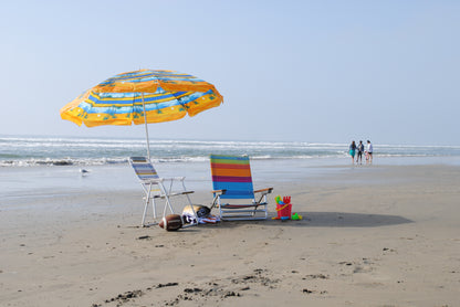 Umbrella rental, beach chairs, football, beach blanket, beach towels, and kids sand toys from Zack's by the Beach. A family walks on the Huntington Beach coastline.